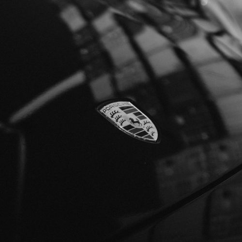 Een zwart-wit foto van het logo van de Porsche Carrera 992 huurauto